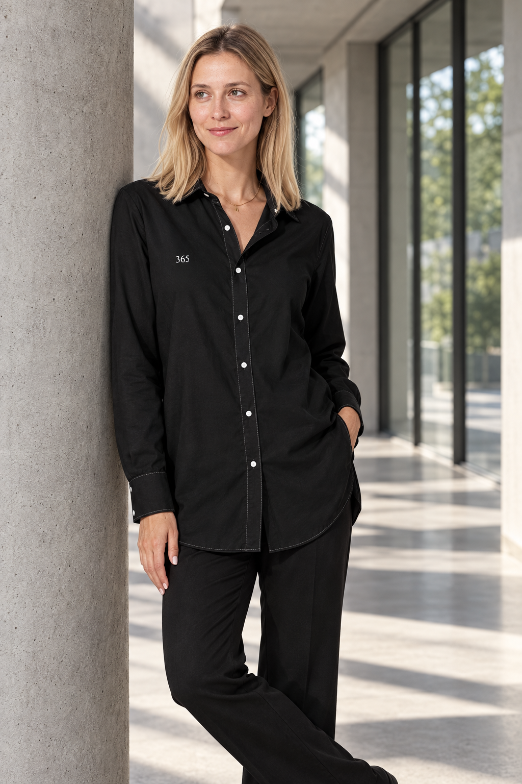 Camisa negra de mujer, tres cuartos apoyada en la columna